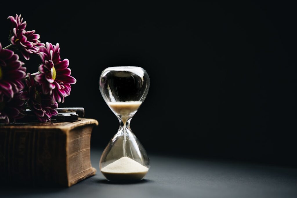 Hourglass beside flowers symbolizing mortality and time